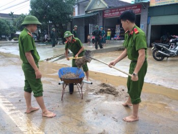 Công an đội mưa dọn bùn đất trên đường